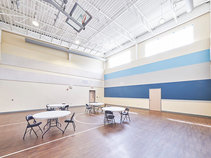 Tables and chairs on an indoor basketball court at Tower Behavioral Health
