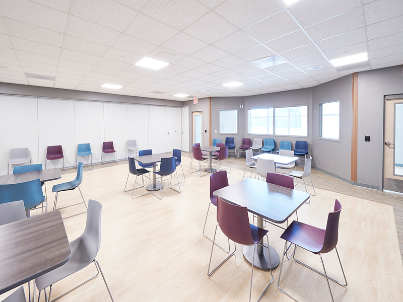 A large room with tables and chairs set up for activities at Tower Behavioral Health